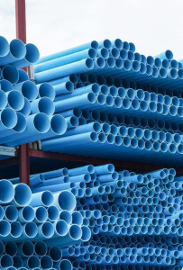 Large stack of blue PVC pipes commonly used for water distribution and plumbing 
