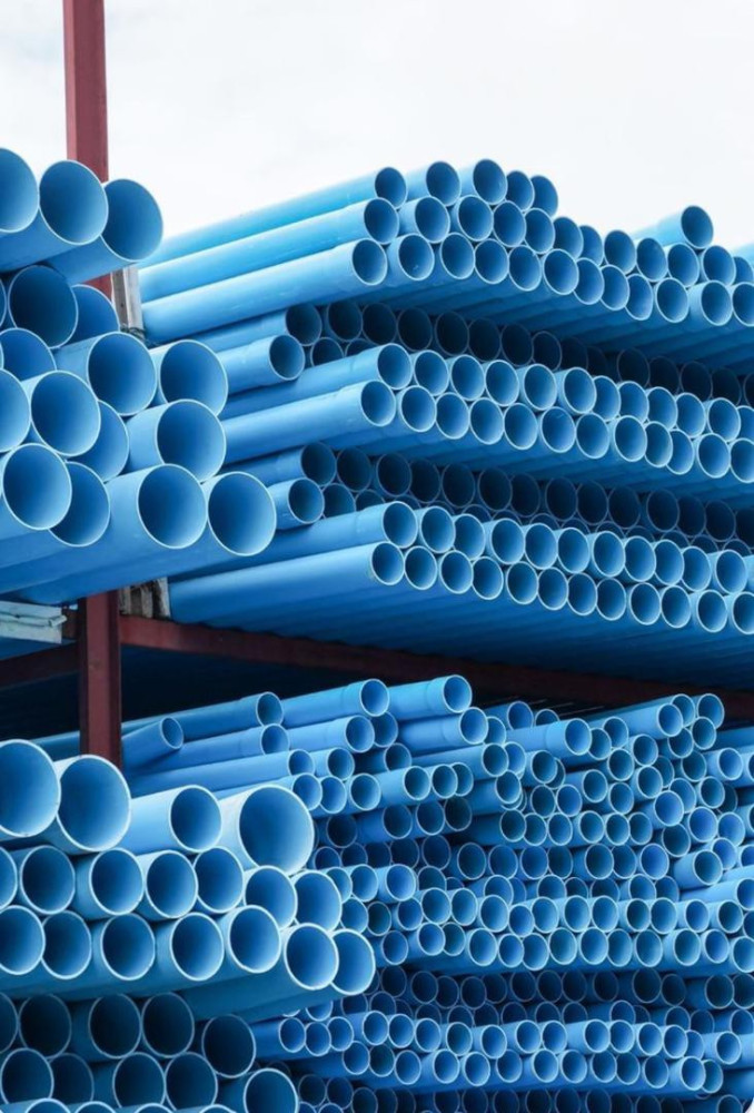 Large stack of blue PVC pipes commonly used for water distribution and plumbing 