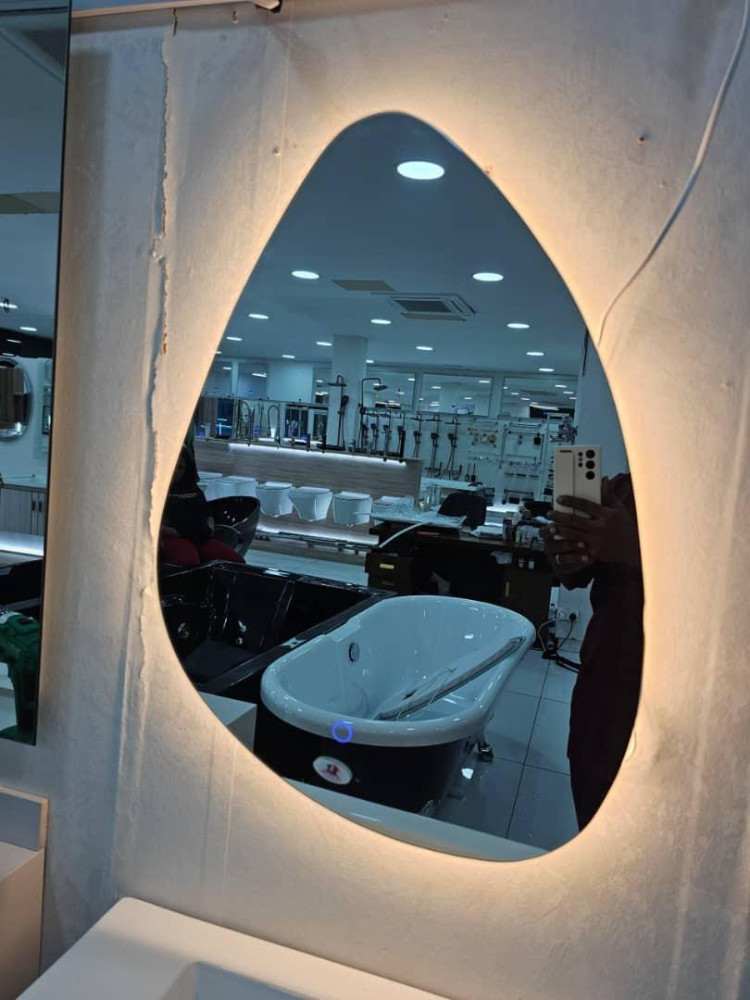 modern teardrop-shaped LED bathroom mirror on display within a showroom