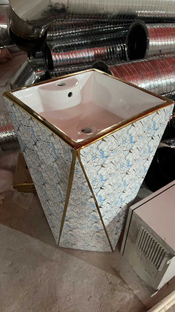 Freestanding ceramicc pedestal bathroom sink with a gold trim and patterned finish 